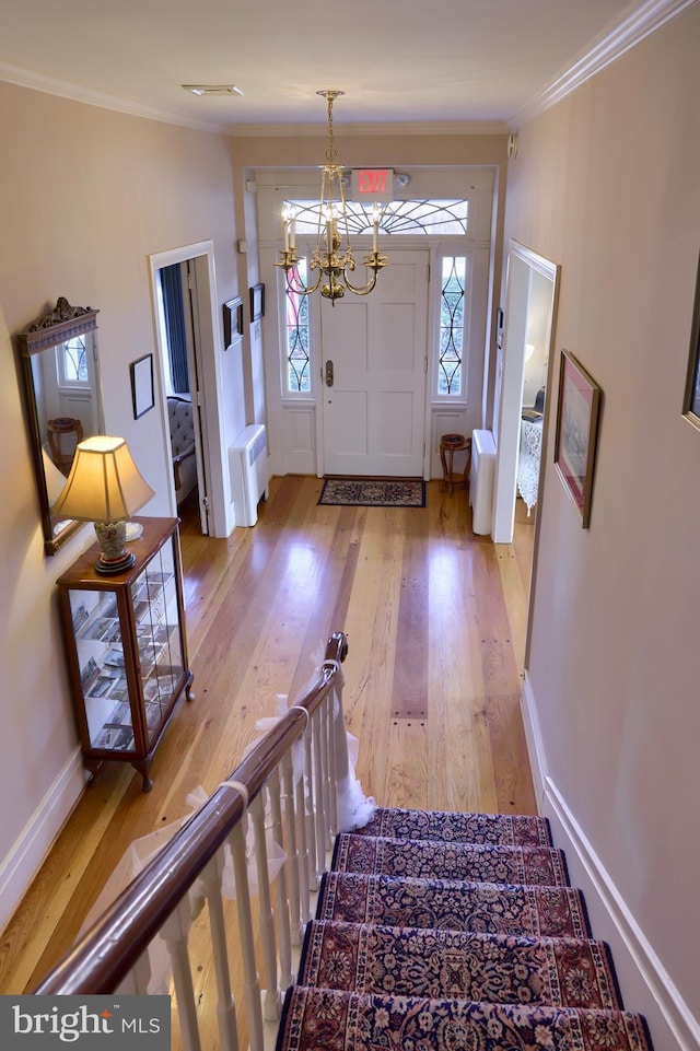 foyer entrance with radiator heating unit, an inviting chandelier, light hardwood / wood-style flooring, and crown molding