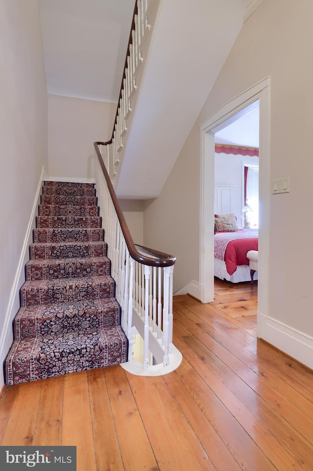 stairs featuring hardwood / wood-style floors and lofted ceiling