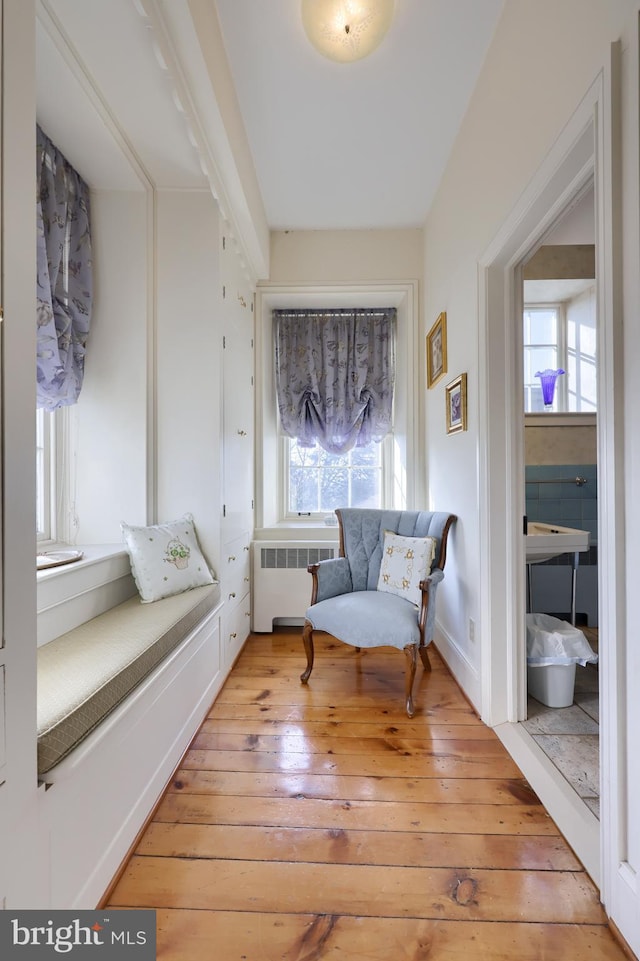 living area with radiator heating unit and hardwood / wood-style flooring