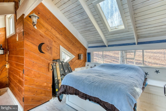 bedroom with vaulted ceiling with skylight, wood ceiling, multiple windows, and wood walls