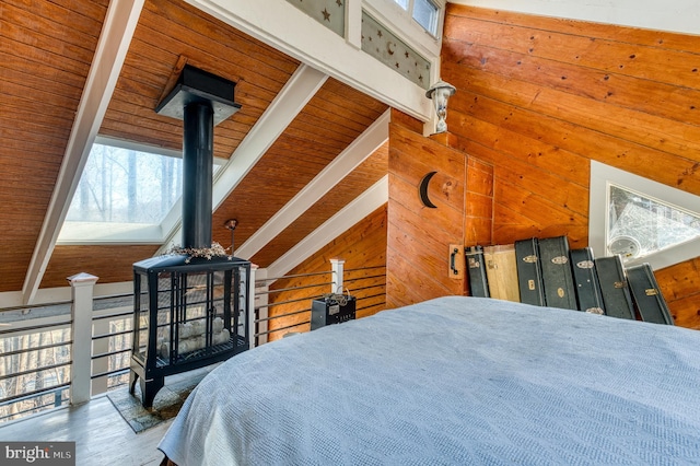 bedroom featuring beamed ceiling, multiple windows, and wood walls