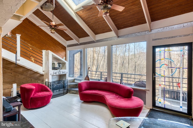 sunroom featuring ceiling fan, lofted ceiling with skylight, a fireplace, and wood ceiling