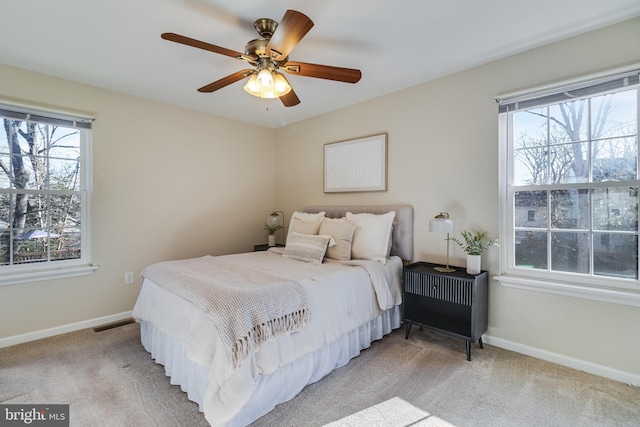 carpeted bedroom featuring multiple windows and ceiling fan