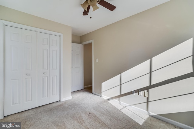 interior space with ceiling fan, light colored carpet, and a closet