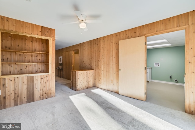 carpeted empty room featuring ceiling fan and wood walls