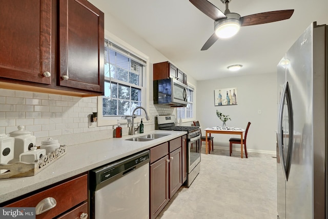 kitchen featuring ceiling fan, sink, stainless steel appliances, light stone counters, and decorative backsplash