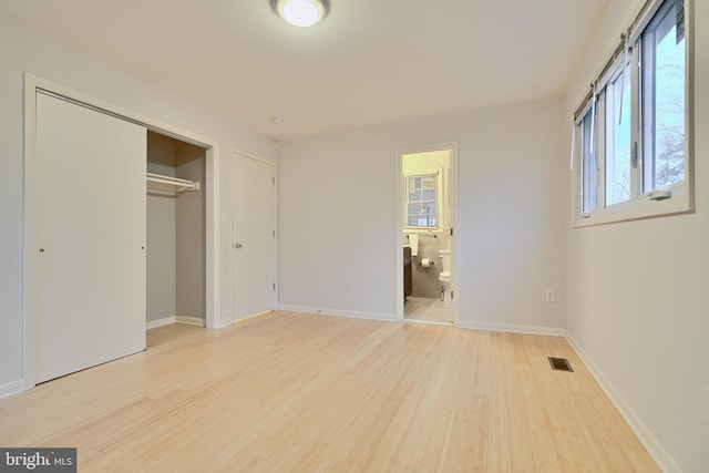 unfurnished bedroom with ensuite bath, a closet, and light hardwood / wood-style flooring