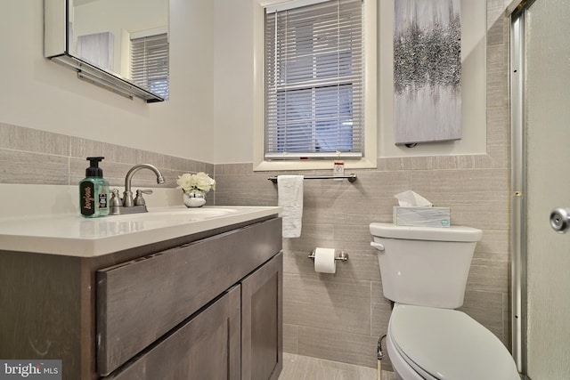 bathroom featuring vanity, toilet, and tile walls