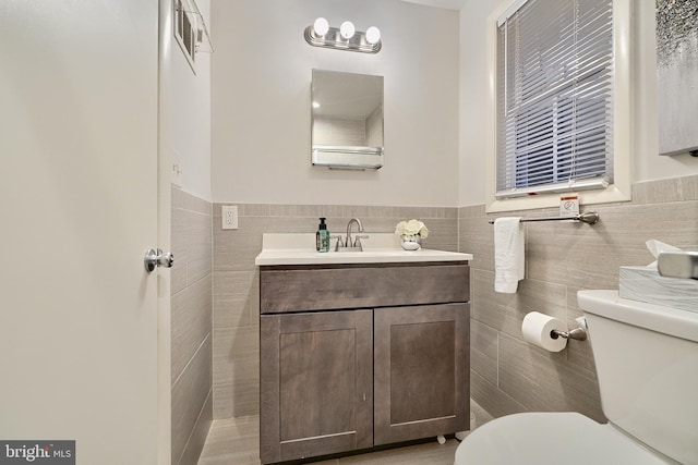 bathroom featuring vanity, toilet, and tile walls