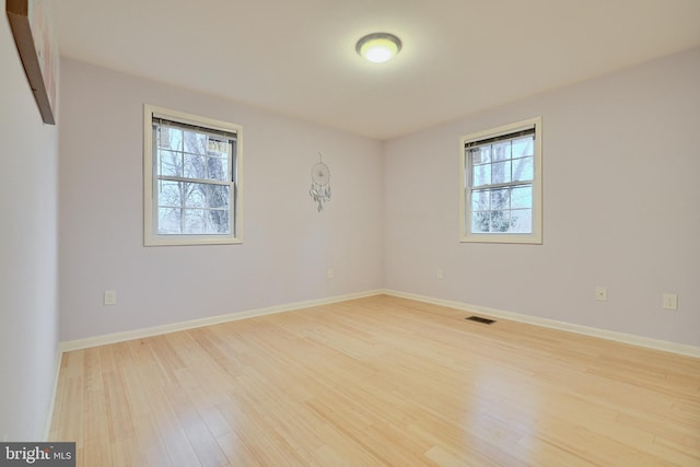 empty room with a healthy amount of sunlight and hardwood / wood-style flooring