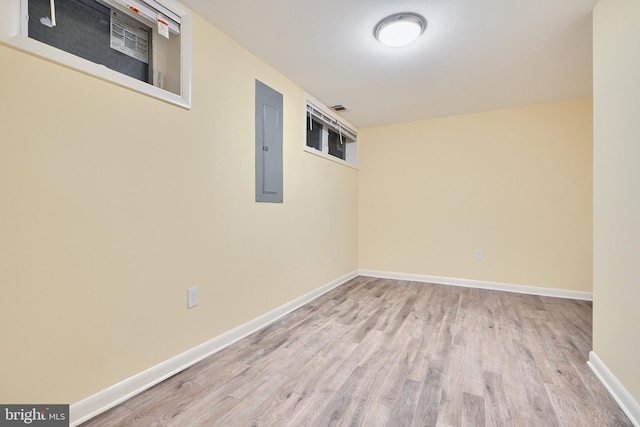 basement with light hardwood / wood-style floors and electric panel