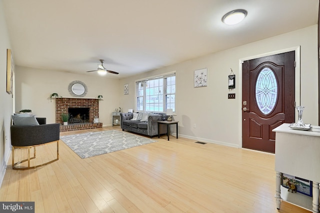 foyer entrance featuring a brick fireplace, ceiling fan, and hardwood / wood-style flooring