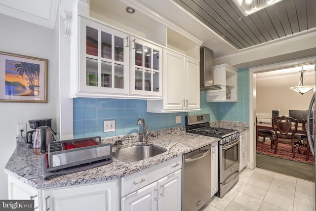 kitchen featuring white cabinets, wall chimney range hood, sink, and appliances with stainless steel finishes