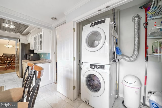 laundry room featuring crown molding, light tile patterned floors, and stacked washer / dryer