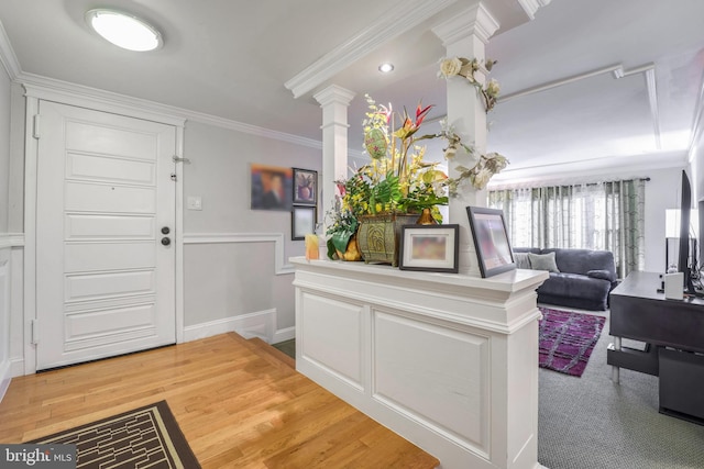 foyer entrance with ornate columns, crown molding, and wood-type flooring