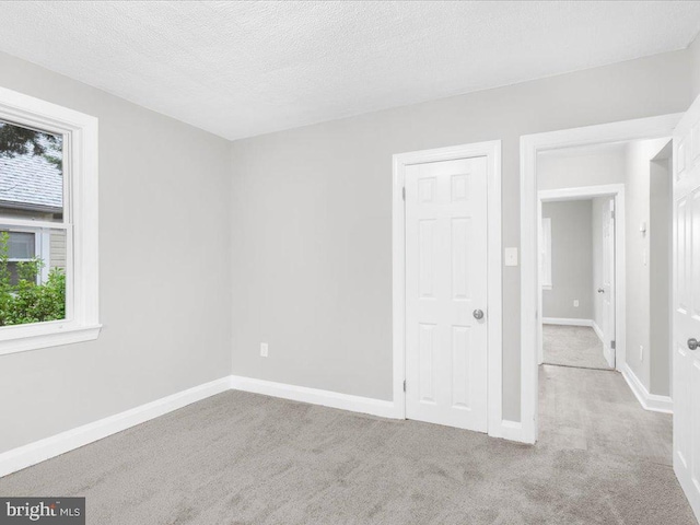 carpeted spare room featuring plenty of natural light and a textured ceiling