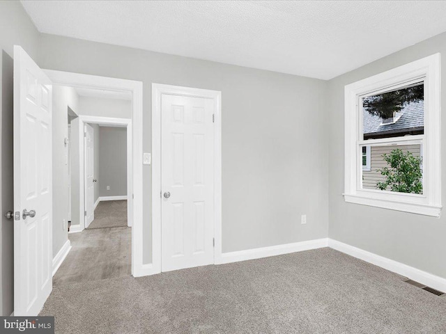 empty room with carpet and a textured ceiling