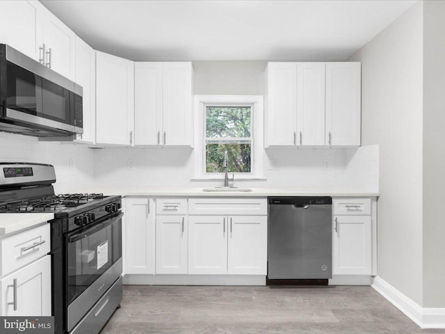 kitchen featuring tasteful backsplash, stainless steel appliances, sink, light hardwood / wood-style flooring, and white cabinetry