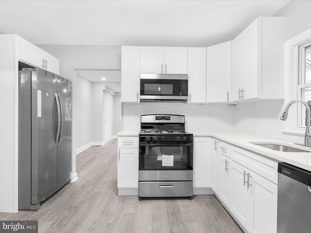 kitchen with backsplash, sink, white cabinetry, and stainless steel appliances