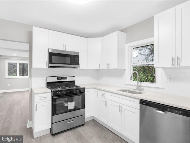 kitchen with appliances with stainless steel finishes, white cabinetry, and sink