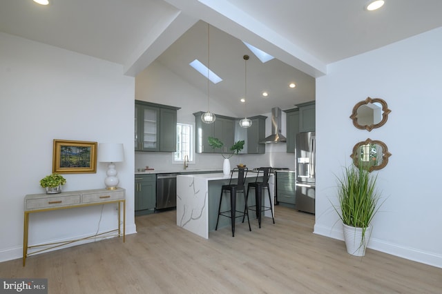 kitchen with a breakfast bar, a center island, hanging light fixtures, wall chimney exhaust hood, and stainless steel appliances