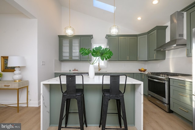 kitchen with a center island, wall chimney exhaust hood, tasteful backsplash, stainless steel gas range oven, and pendant lighting