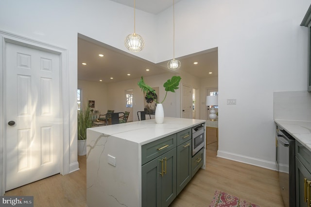 kitchen featuring light stone countertops, stainless steel dishwasher, light hardwood / wood-style floors, a kitchen island, and hanging light fixtures