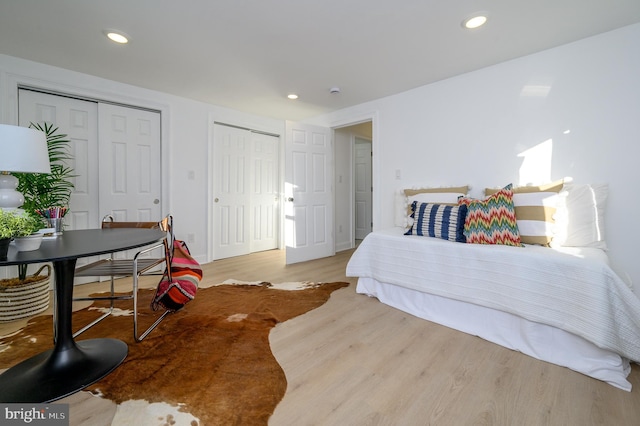 bedroom with multiple closets and light wood-type flooring