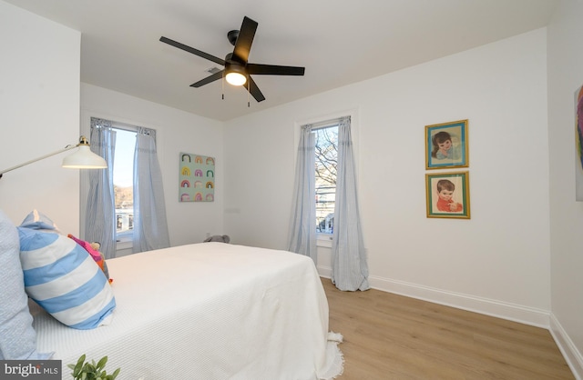 bedroom featuring multiple windows, ceiling fan, and light hardwood / wood-style flooring