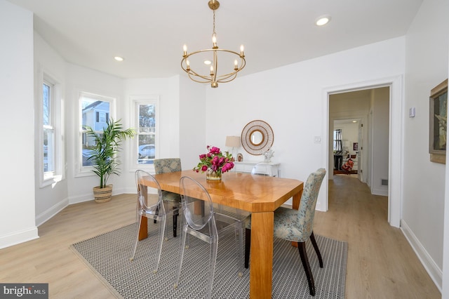 dining room with light wood-type flooring and an inviting chandelier