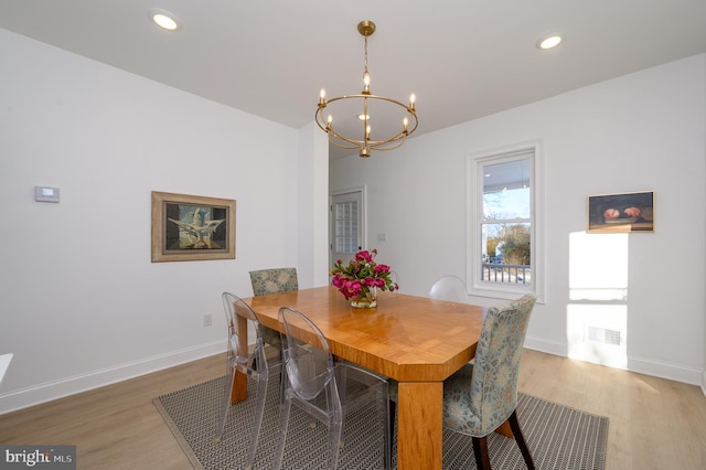 dining room with wood-type flooring and an inviting chandelier