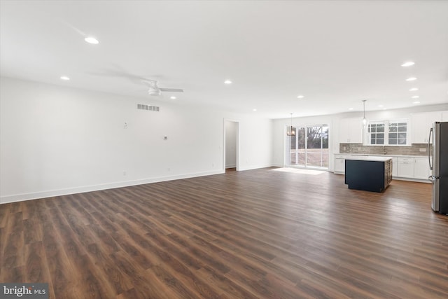 unfurnished living room with ceiling fan and dark wood-type flooring