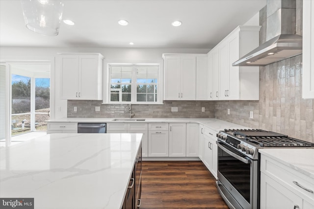 kitchen featuring white cabinets, wall chimney range hood, sink, appliances with stainless steel finishes, and light stone counters