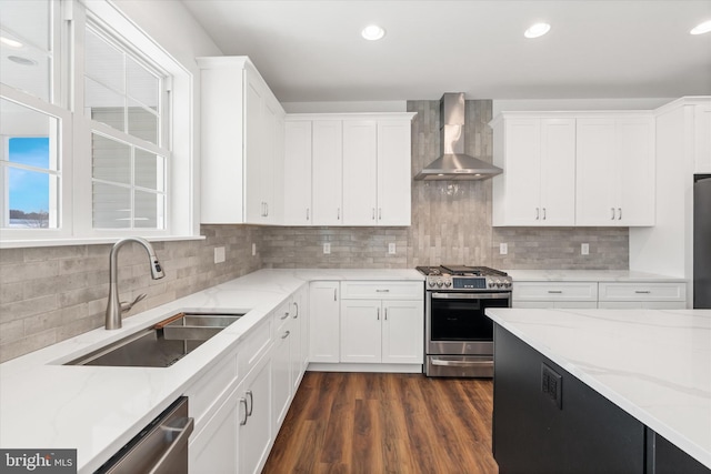 kitchen with wall chimney exhaust hood, light stone counters, white cabinetry, and stainless steel appliances