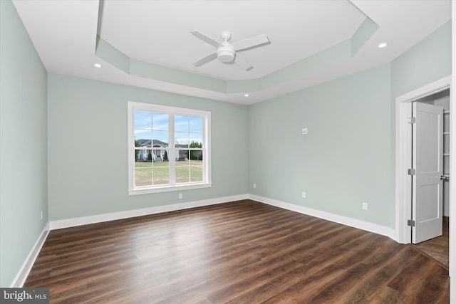 empty room featuring dark hardwood / wood-style flooring, a tray ceiling, and ceiling fan