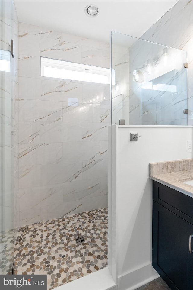 bathroom featuring tiled shower and vanity