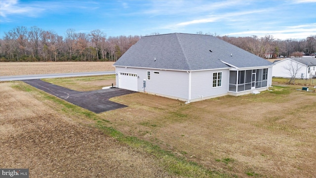 back of house featuring a sunroom, a yard, and a garage