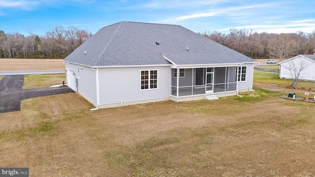 rear view of house featuring a sunroom and a lawn