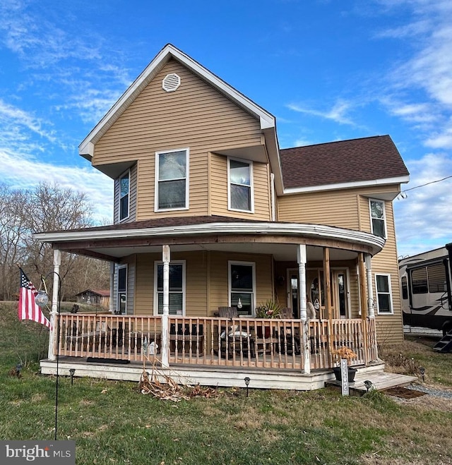 farmhouse featuring a porch, a shingled roof, and a front yard