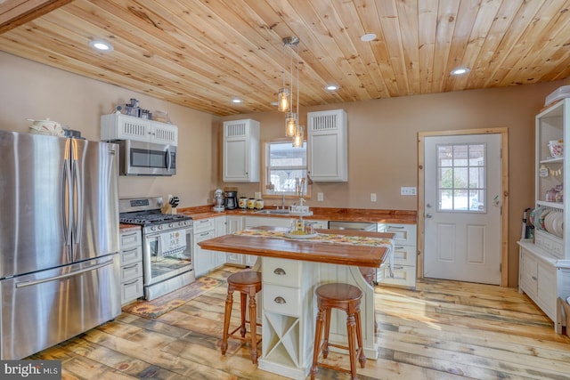 kitchen featuring white cabinetry, a kitchen breakfast bar, wooden counters, a kitchen island, and appliances with stainless steel finishes