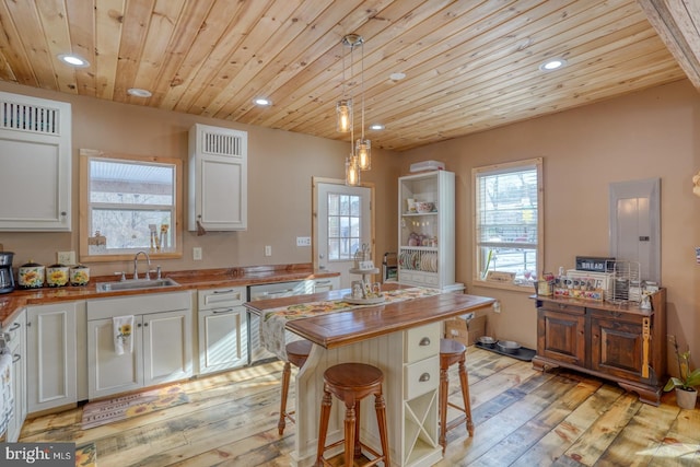 kitchen featuring wooden ceiling, butcher block countertops, pendant lighting, a breakfast bar area, and white cabinets