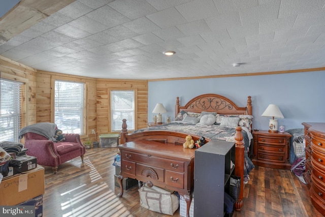 bedroom with wood walls, ornamental molding, and dark wood-type flooring