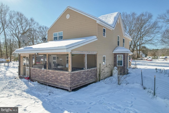 snow covered house featuring a sunroom