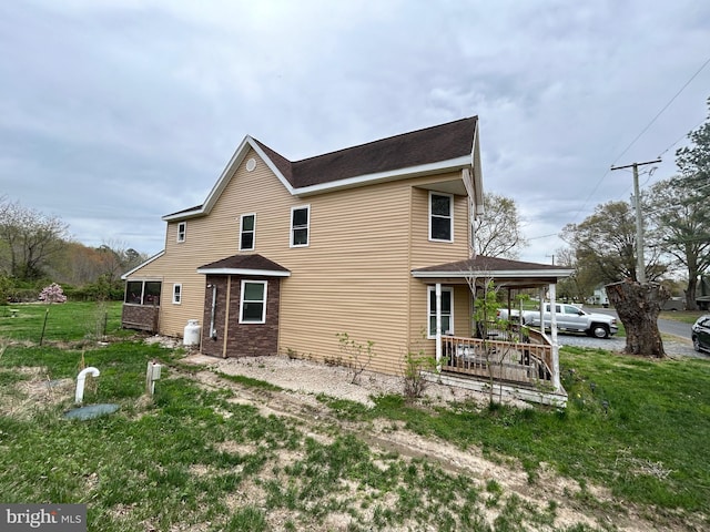 exterior space with roof with shingles, a porch, and a yard