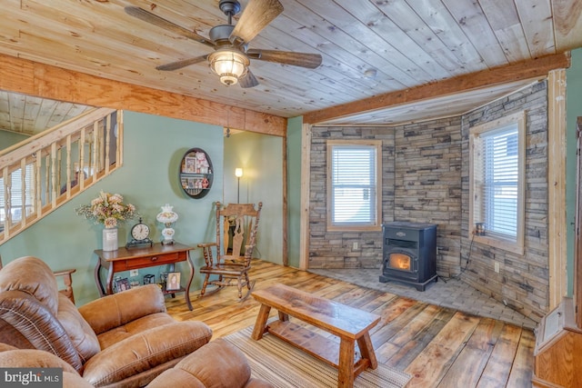 living room featuring a wood stove, ceiling fan, wooden ceiling, beamed ceiling, and hardwood / wood-style flooring