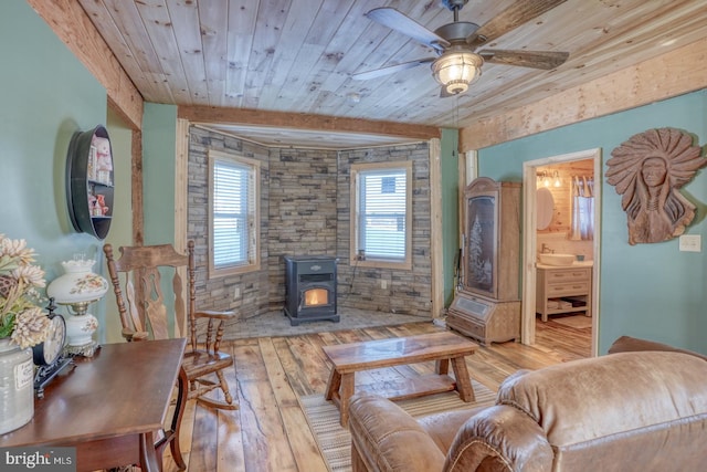 living room with light hardwood / wood-style floors, a wood stove, ceiling fan, and wood ceiling