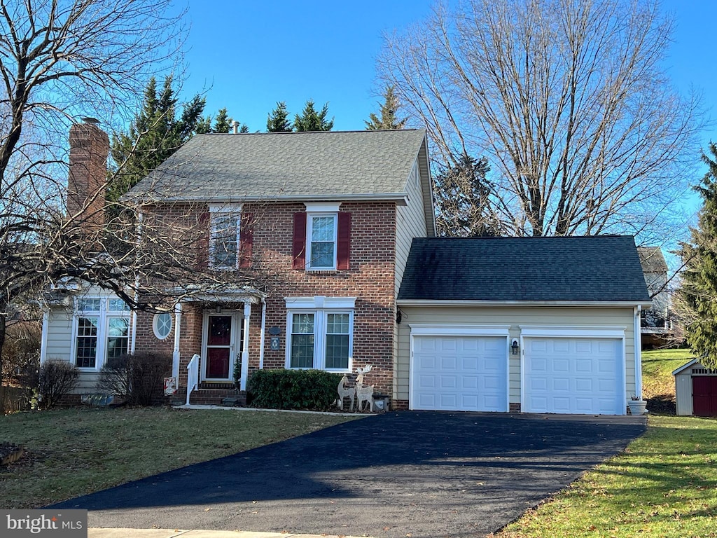 colonial-style house featuring a garage and a front yard