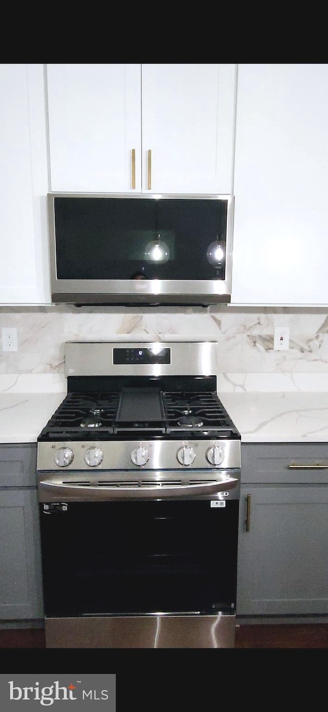 kitchen featuring white cabinetry, appliances with stainless steel finishes, backsplash, and gray cabinetry