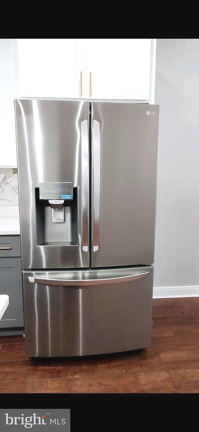 details featuring dark wood finished floors, gray cabinets, light countertops, stainless steel refrigerator with ice dispenser, and backsplash