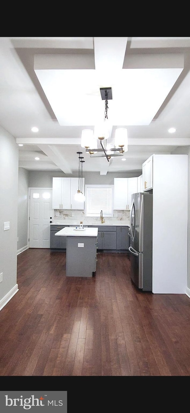 kitchen featuring dark wood-style flooring, light countertops, freestanding refrigerator, white cabinets, and a kitchen island